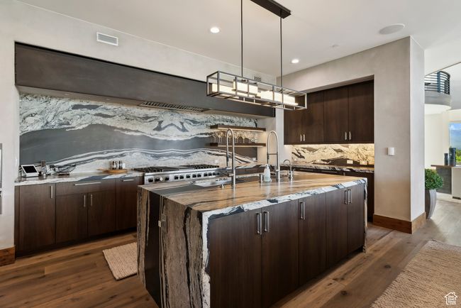 Kitchen featuring backsplash, dark wood-style flooring, dark brown cabinetry, light stone countertops, and recessed lighting | Image 13