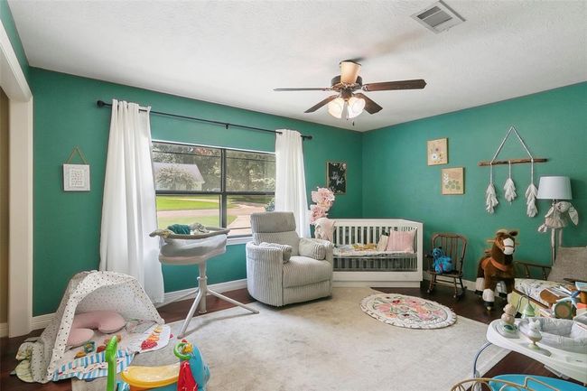 This cozy nursery features teal walls and a large window that lets in plenty of natural light. It includes a crib, armchair, and playful decor, creating a warm and inviting atmosphere for a little one. | Image 31