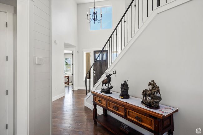 Entryway featuring a towering ceiling, dark wood-style flooring, baseboards, a chandelier, and stairs | Image 7