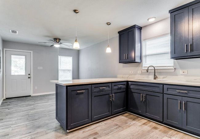 Kitchen featuring visible vents, a sink, light wood-type flooring, a ceiling fan, and a peninsula | Image 7
