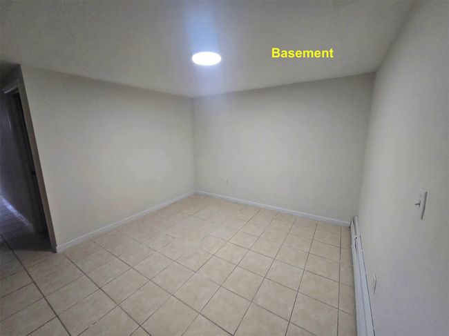 Empty room featuring a baseboard heating unit, light tile patterned floors, and baseboards | Image 14