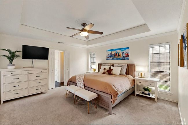 Bedroom featuring light colored carpet, multiple windows, crown molding, and a raised ceiling | Image 17