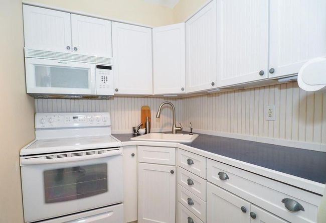Kitchen with white cabinetry, a sink, and white appliances | Image 6