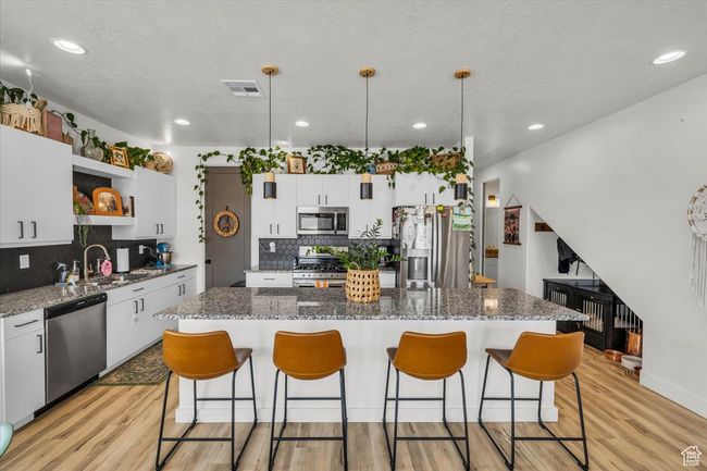 Kitchen with a kitchen island, open shelves, light wood-style flooring, and stainless steel appliances | Image 12
