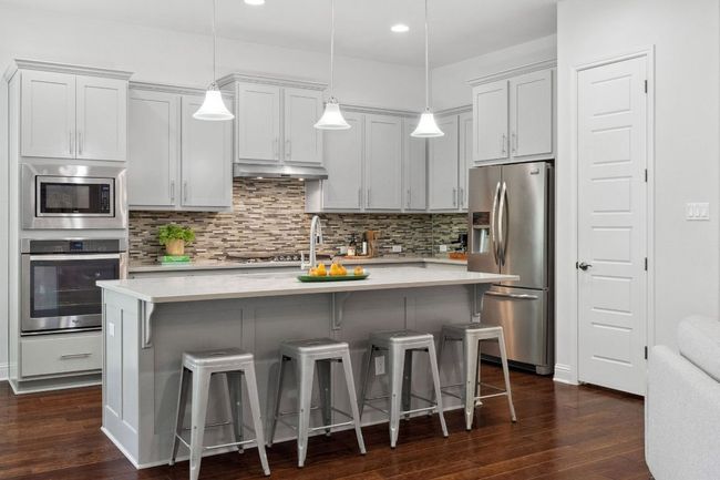 The kitchen features soft-close shaker cabinetry and luxurious quartz counters. | Image 13