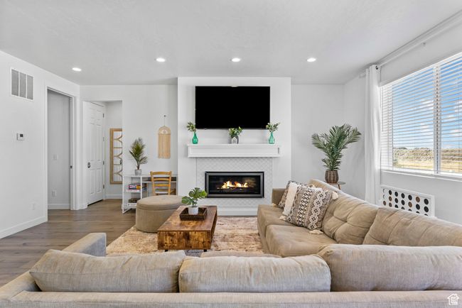 Living area with a fireplace, recessed lighting, visible vents, wood finished floors, and baseboards | Image 24