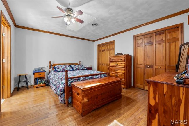 Bedroom featuring light wood finished floors, two closets, and ceiling fan | Image 69