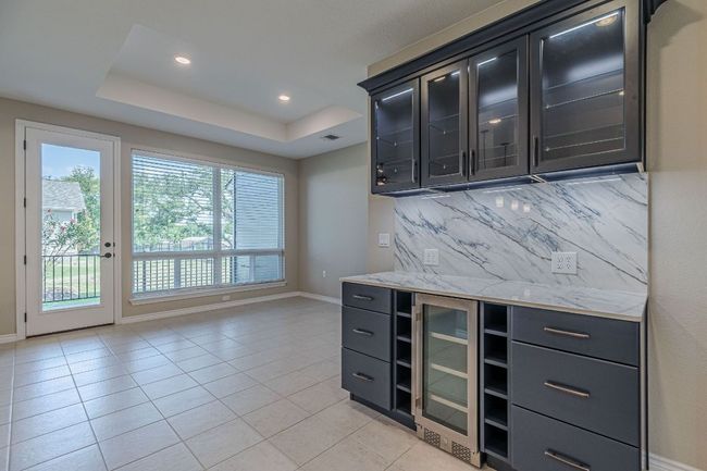 Bar with a tray ceiling, wine cooler, light tile patterned floors, backsplash, and recessed lighting | Image 10