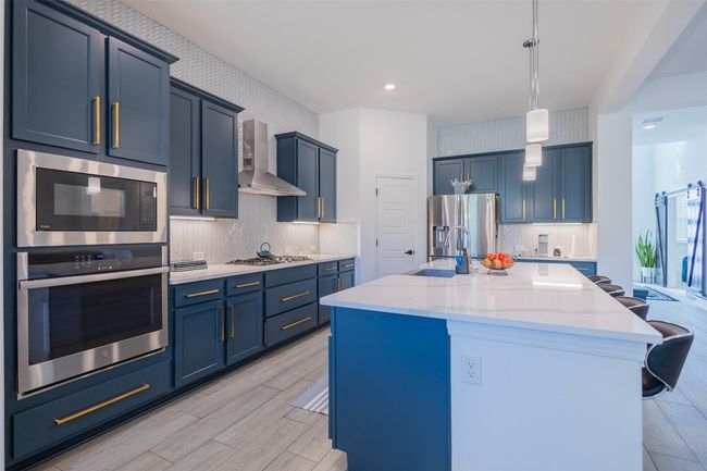 The gourmet kitchen is a harmonious as ever and boasts a large center island/breakfast bar and shimmering quartz countertops. | Image 11