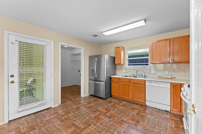 Kitchen with white dishwasher, stainless steel fridge, range, light countertops, and tasteful backsplash | Image 16