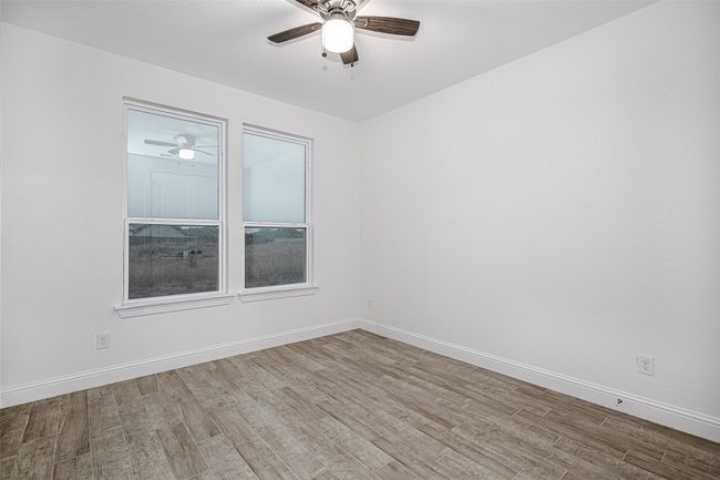 Empty room with a ceiling fan, wood finished floors, and baseboards | Image 14