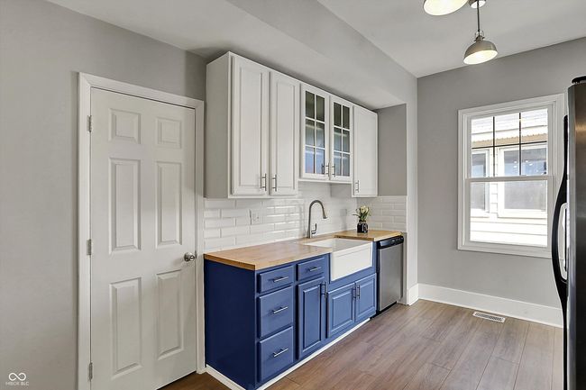 kitchen featuring a sink, visible vents, blue cabinetry, dishwasher, and wooden counters | Image 20