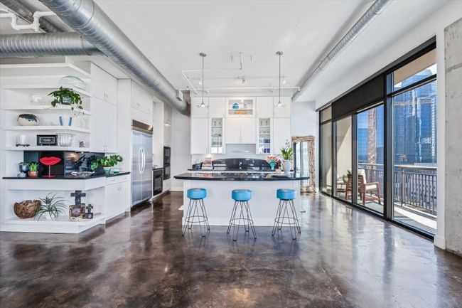 Kitchen featuring Ink granite countertops, white cabinets, concrete floors, a breakfast bar area, and open shelves | Image 11