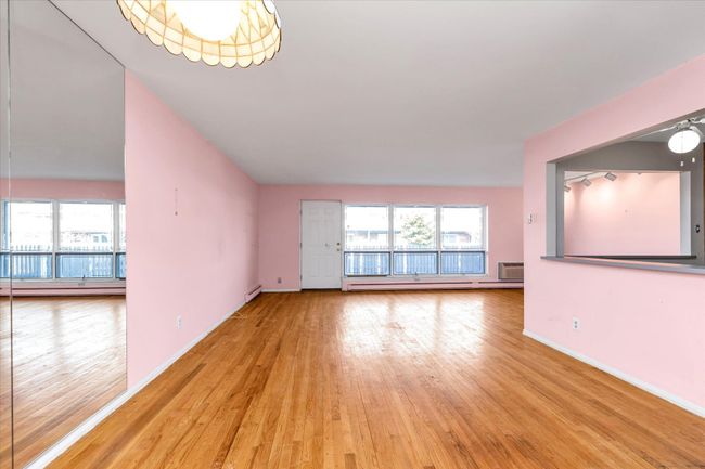 Unfurnished living room with a healthy amount of sunlight, light wood-style flooring, baseboards, and baseboard heating | Image 11