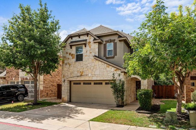 View of front of house with stone siding, driveway, an attached garage, stucco siding, and a shingled roof | Image 17