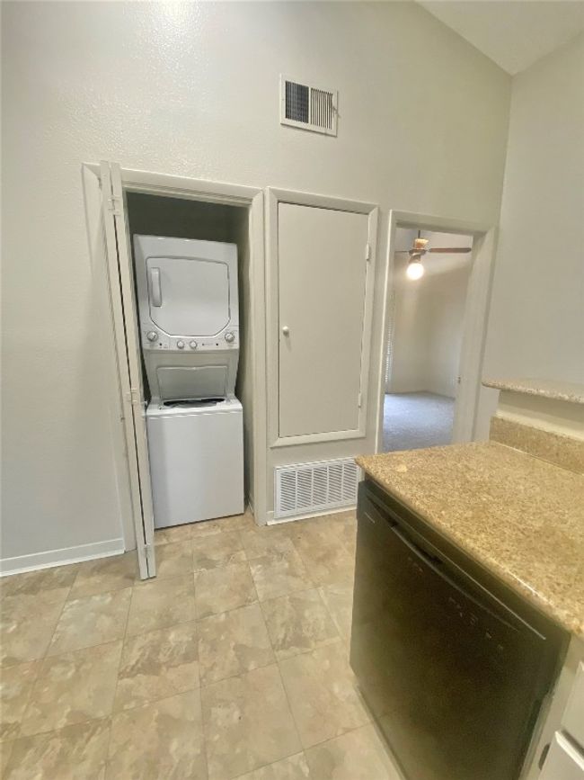 Laundry area featuring stacked washer / drying machine, a ceiling fan, visible vents, and laundry area | Image 16