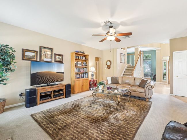 Living area with a ceiling fan, stairs, carpet, decorative columns, and baseboards | Image 6