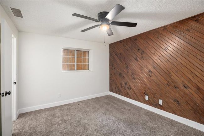 Spare room with wood walls, a textured ceiling, a ceiling fan, baseboards, and carpet floors | Image 14