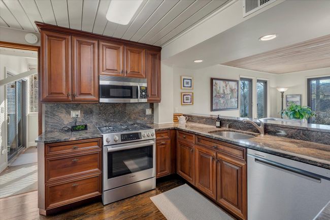 Kitchen with stainless steel appliances, sink, and wooden ceiling | Image 11