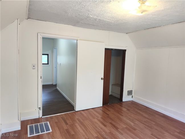 Unfurnished bedroom featuring lofted ceiling, wood finished floors, a textured ceiling, baseboards, and a closet | Image 39