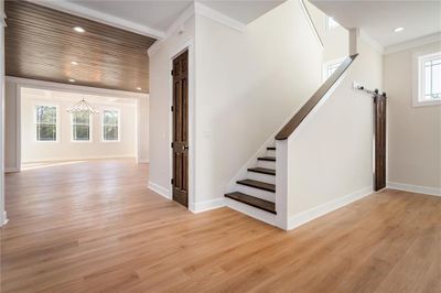 Stairway with light hardwood / wood-style flooring, ornamental molding, a barn door, a wealth of natural light, and a chandelier | Image 2