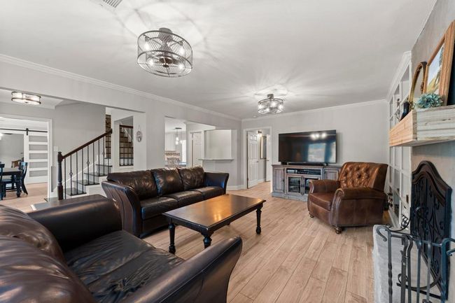 Living room features a cozy fireplace with a decorative mantel. The space is well-lit with an open view to the kitchen and dining area, creating a seamless flow for entertaining. | Image 7