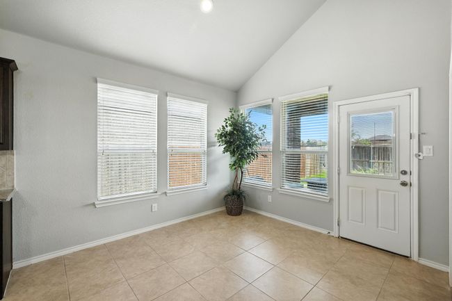Unfurnished dining area featuring light tile patterned flooring and high vaulted ceiling | Image 8