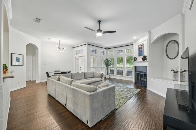 Living room with ornamental molding, arched walkways, ceiling fan, a chandelier, and a tile fireplace | Image 17