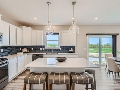 (Photo of a decorated model, actual homes finishes will vary) Welcome to the Lewis! This spacious kitchen features a large center island, quartz countertops, LVP floors, stainless appliances and more. | Image 1