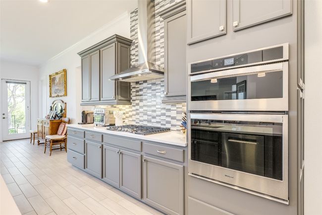 Kitchen with appliances with stainless steel finishes, ornamental molding, backsplash, wall chimney exhaust hood, and gray cabinets | Image 7