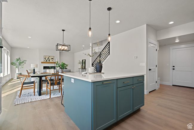 Kitchen featuring light wood finished floors, recessed lighting, decorative light fixtures, light countertops, and a center island | Image 14