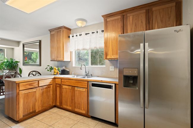 Kitchen featuring appliances with stainless steel finishes, a sink, a peninsula, light countertops, and light tile patterned floors | Image 18