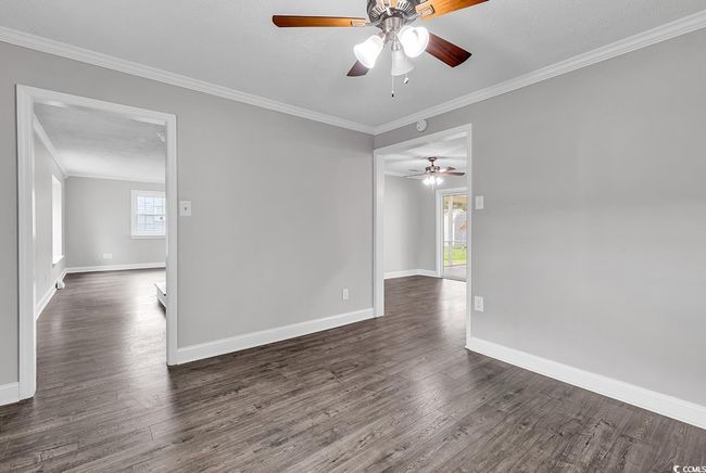 Spare room with crown molding, a ceiling fan, and dark wood-style floors | Image 7
