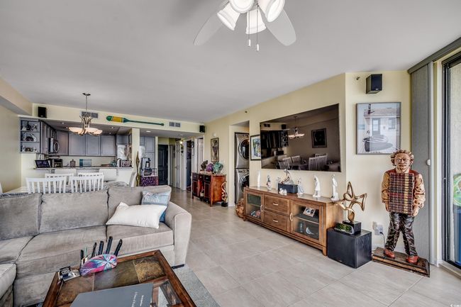 Living room featuring stacked washer / drying machine, a chandelier, ceiling fan, and light tile patterned floors | Image 11
