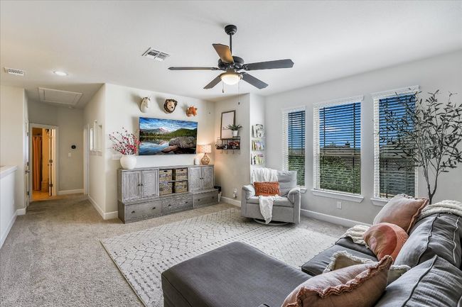Living area featuring a ceiling fan, attic access, carpet, and visible vents | Image 15