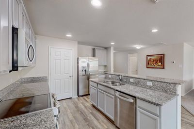 Kitchen featuring sink, light stone countertops, stainless steel appliances, and light hardwood / wood-style floors | Image 2