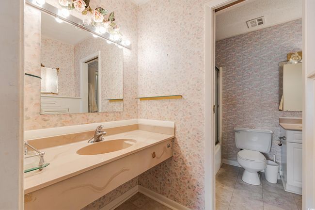 Full bathroom featuring toilet, vanity, shower / tub combination, tile patterned flooring, and wallpapered walls | Image 22