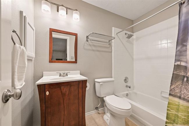 Another full bathroom with a sleek wood vanity, updated lighting, and a clean white tile tub/shower combo is there to serve the previous bedroom. | Image 21