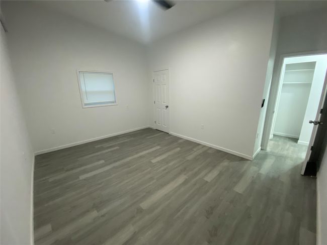 Spare room with dark wood-style floors, baseboards, vaulted ceiling, and a ceiling fan | Image 13