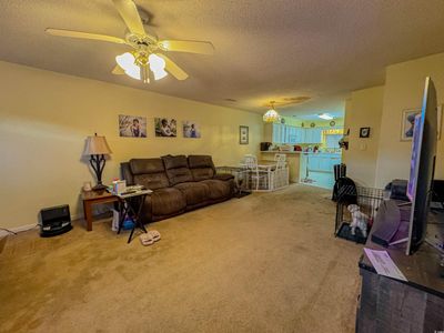 Carpeted living room featuring a textured ceiling and ceiling fan | Image 3