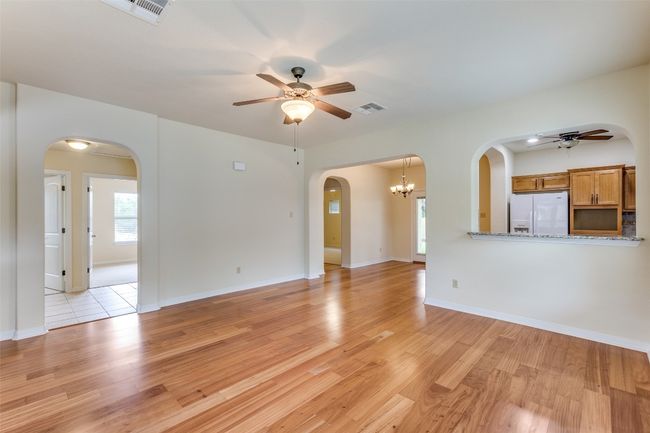 Unfurnished living room with ceiling fan, arched walkways, and light wood-style floors | Image 10