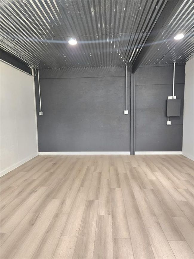 This photo shows the other side of the barnmodern picture of the barn with light wood flooring and a dark gray accent wall. The ceiling is covered with corrugated metal panels, giving it an industrial feel. There are exposed electrical conduits, adding to the contemporary design. | Image 41