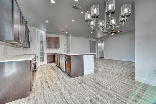 Kitchen featuring appliances with stainless steel finishes, sink, decorative light fixtures, decorative backsplash, and a center island with sink | Image 30