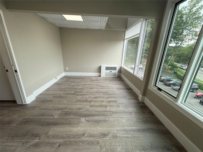 Unfurnished room featuring healthy amount of natural light, wood finished floors, heating unit, and an ornate ceiling | Image 6