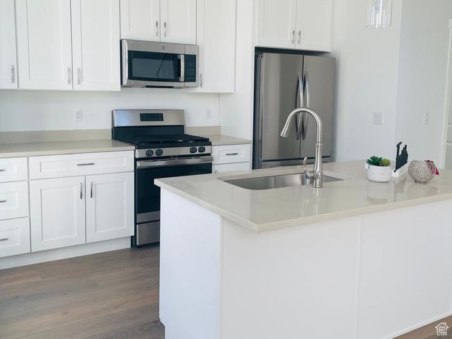 Kitchen with appliances with stainless steel finishes, wood finished floors, and white cabinetry | Image 4