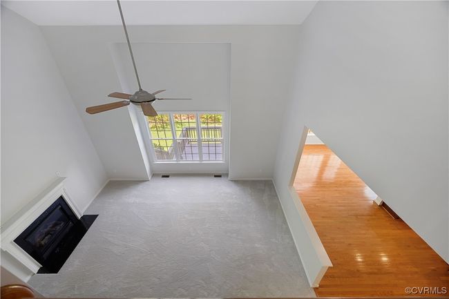 Unfurnished living room featuring carpet floors, baseboards, a fireplace, a towering ceiling, and a ceiling fan | Image 28