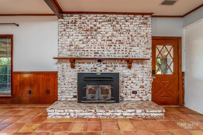 Interior details featuring a brick fireplace, wood walls, and ornamental molding | Image 5