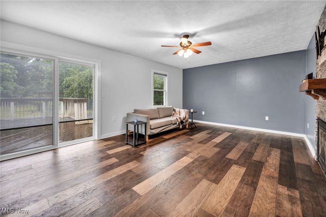 Living room featuring ceiling fan, wood finished floors, and a stone surround on a gas fireplace | Image 17