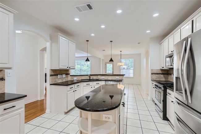 Kitchen with stainless steel appliances, arched walkways, backsplash, a peninsula, and light tile patterned floors | Image 9