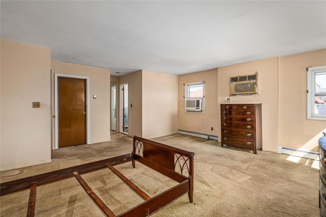 Bedroom featuring multiple windows, a wall unit AC, a baseboard heating unit, and carpet flooring | Image 17